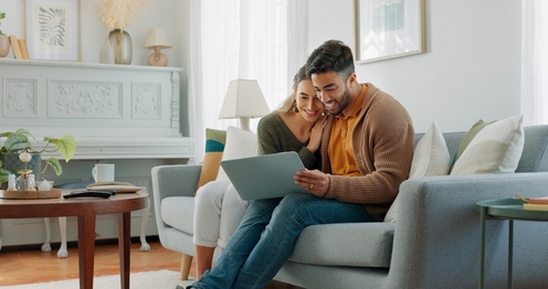 Smiling family couple sitting in a colorful sofa watching a tablet together