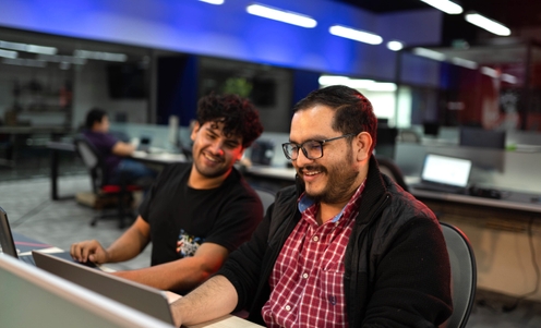 Two business professionals collaborating in an office setting, focused on a computer screen.