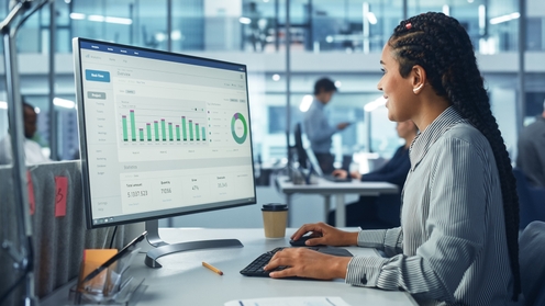 Financial anayst woman reviewing statistics and financial data in a computer screen in a modern high tech office