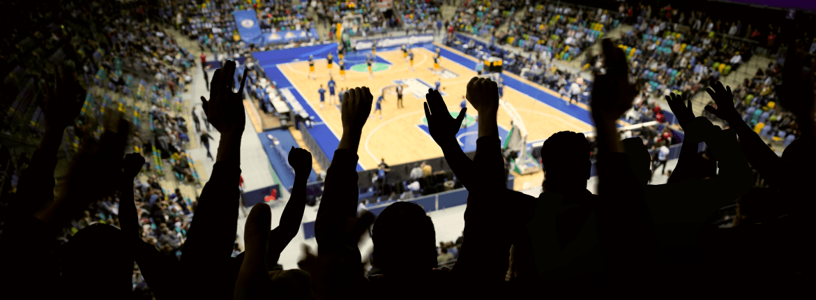 Fans in a stadium crowd cheering an NBA team in a tournament game