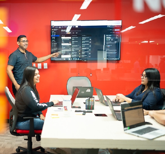 A diverse group of individuals collaborating around a table, each using their laptops for a productive discussion.