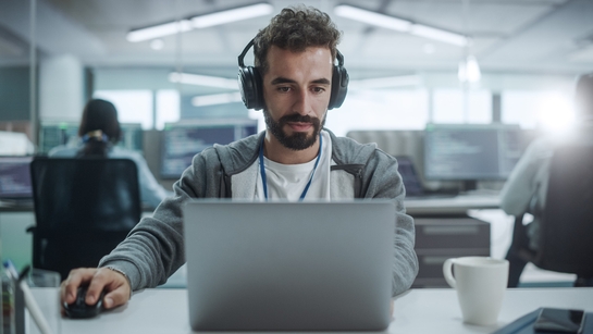 Infrastructure software developer analyzing information in a laptop at a modern office