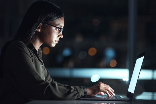 Female business worker typing digital solutions in a laptop at night