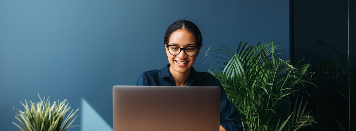 Smiling female developer staring at a grey laptop in an office setting